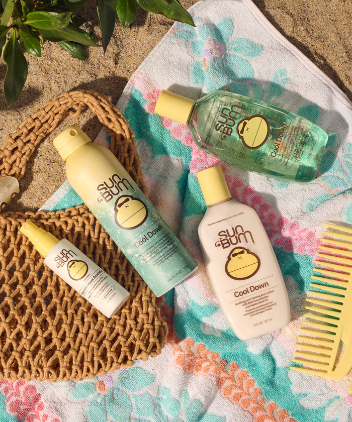 Sun Bum Hypochlorous Acid Mist bottle on a floral towel with other Sun Bum Cool Down products and a comb nearby
