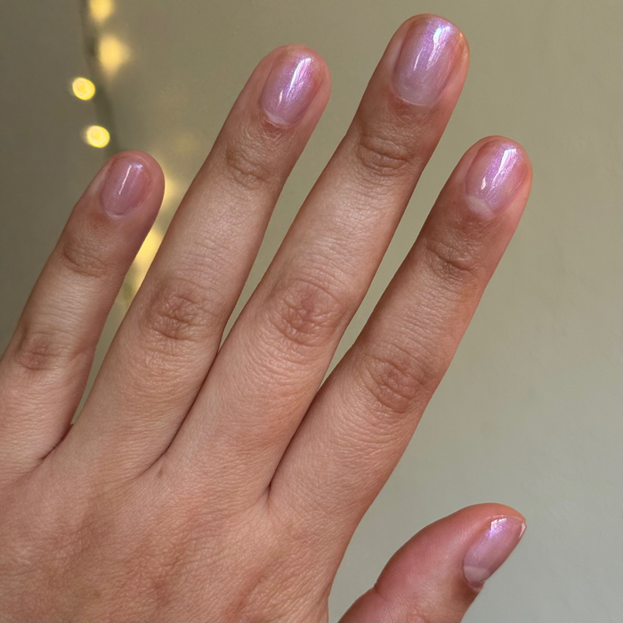 Hand with nails painted in glowing pearly white iridescent using BAROQUE Gel for an elegant at-home mani look