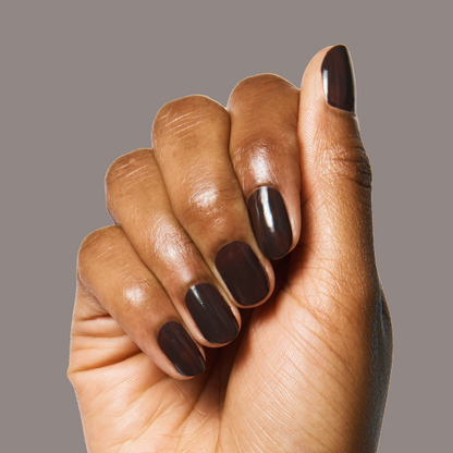 Hand with Dark Chocolate nail polish on medium-length rounded nails against neutral background