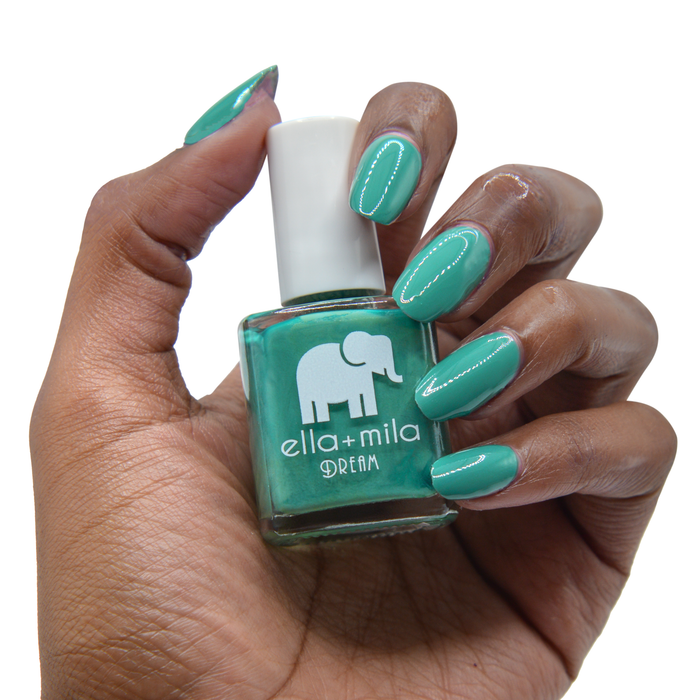 Daydreamer viridian green nail polish on a deep skin tone, hand holding the bottle