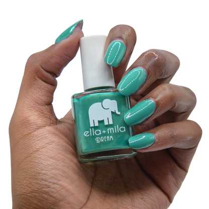Daydreamer viridian green nail polish on a deep skin tone, hand holding the bottle