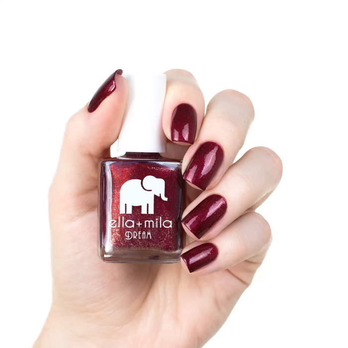 Dorothy's Stilettos red shimmer nail polish manicure on a light skin tone with the bottle
