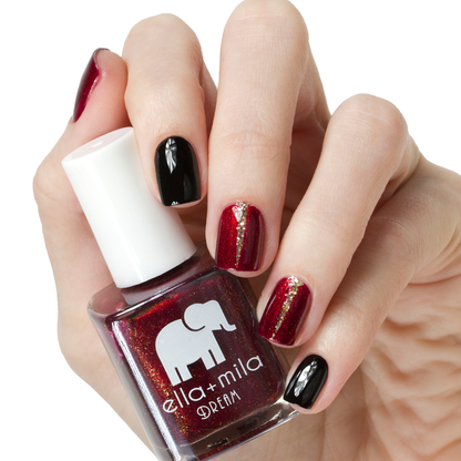 Dorothy's Stilettos deep red nail polish with a black accent nail, holding the bottle