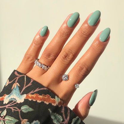 First Class icy green nail polish manicure on a medium skin tone with rings and a floral sleeve