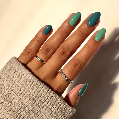 First Class icy green and teal mix-and-match manicure with rings in sunlight