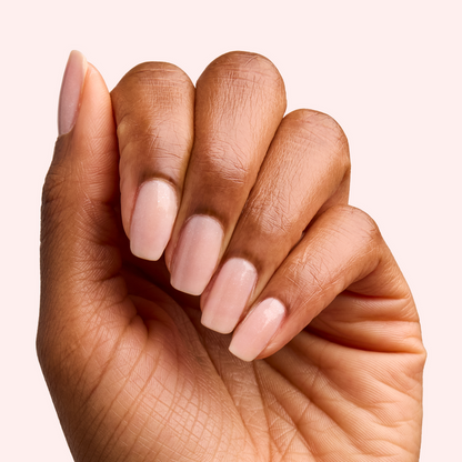 Hand displaying manicure with FIRST DATE nail polish in milky strawberry pink and fine silver shimmer
