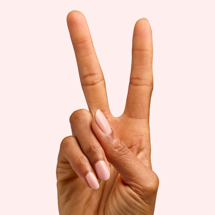 Hand showing peace sign with nails polished in FIRST DATE sheer strawberry pink with silver shimmer manicure