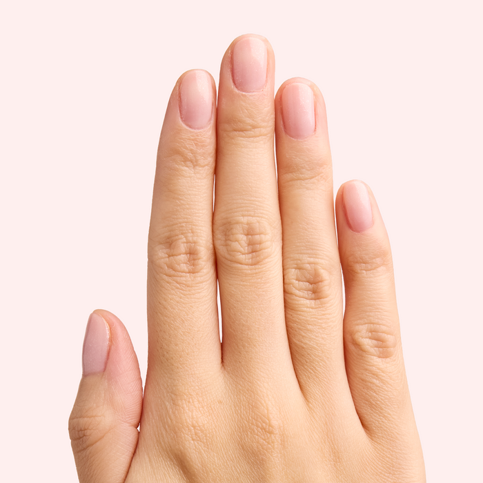 Hand showing natural manicure with FIRST DATE sheer milky strawberry pink and ultra fine silver shimmer polish