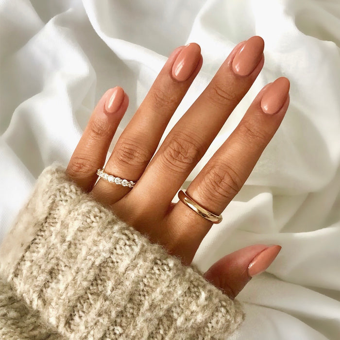 Global Goddess sandy nude nail polish manicure on a medium skin tone with gold rings