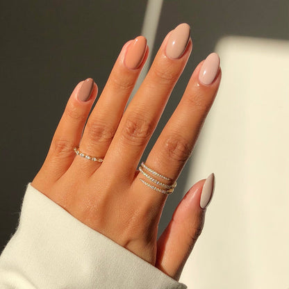 Global Goddess nude and coral mix-and-match manicure with rings in sunlight