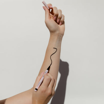 A woman applying Lash & Dash® Glue Liner- Satin Black to her arm.