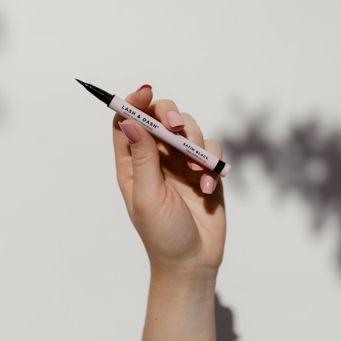 A woman holding the Lash & Dash® Glue Liner- Satin Black.