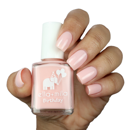 Lucky Seventh nude baby pink nail polish on a medium skin tone, hand holding the bottle