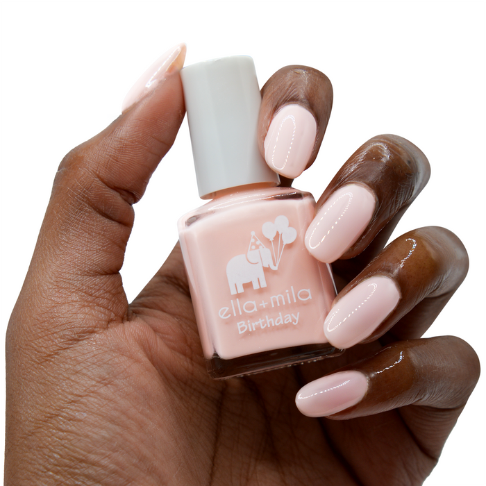 Lucky Seventh nude baby pink nail polish on a deep skin tone, hand holding the bottle