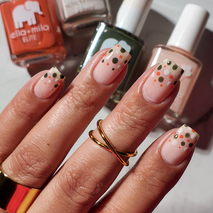 Lucky Seventh nude pink with rust and green flower nail art, holding two bottles