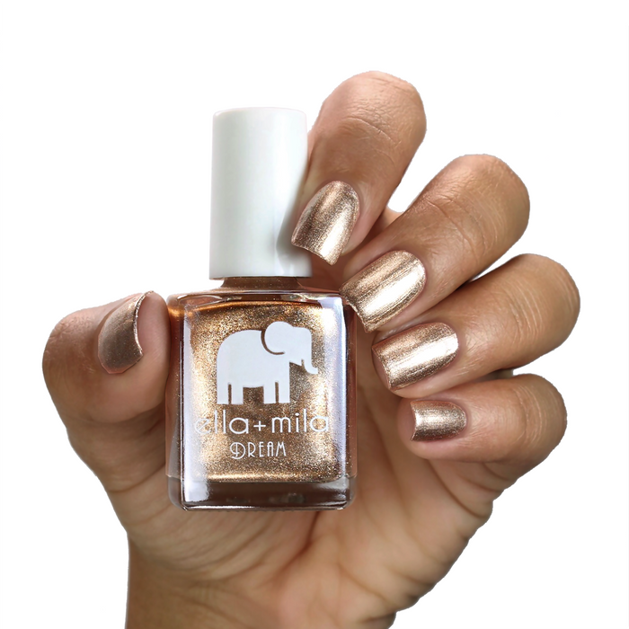 Mirage metallic gold nail polish on a medium skin tone, hand holding the bottle