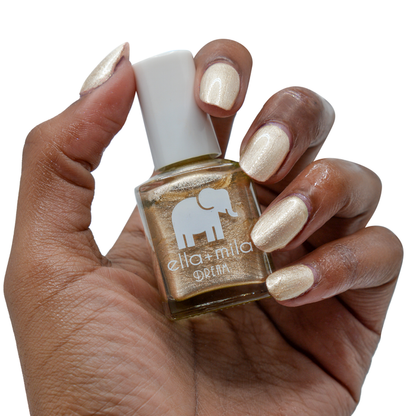 Mirage metallic gold nail polish on a deep skin tone, hand holding the bottle