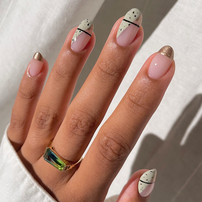 Mirage metallic gold French tip nail art on a medium skin tone in sunlight