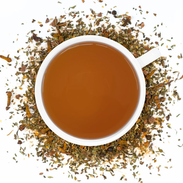 A white cup of Organic Antioxidant Boost Tea surrounded by the loose leaf blend.