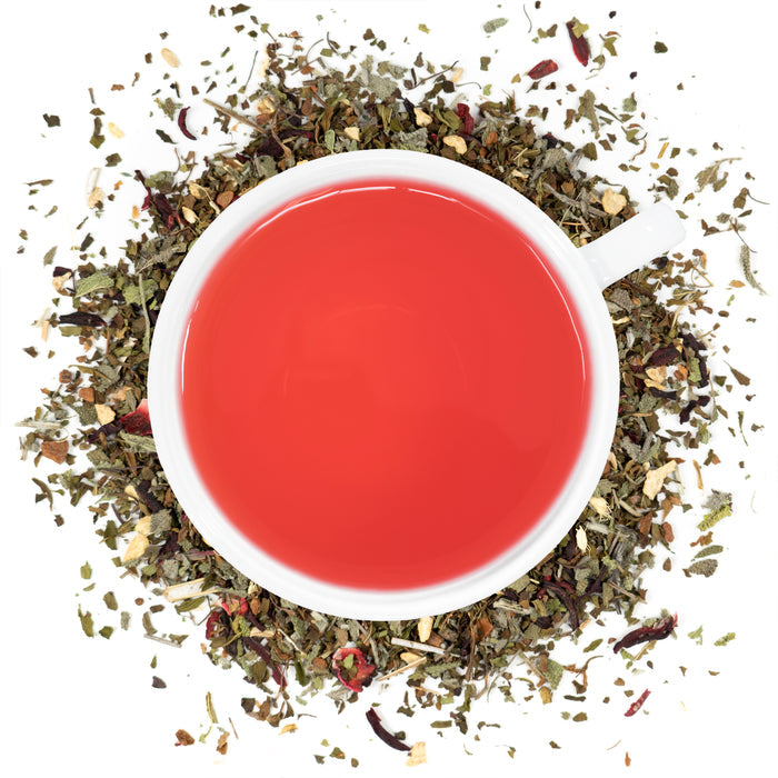 A white cup filled with Organic Sugar Crush Tea surrounded by the loose leaf blend.