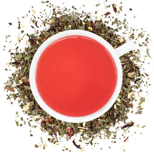 A white cup filled with Organic Sugar Crush Tea surrounded by the loose leaf blend.