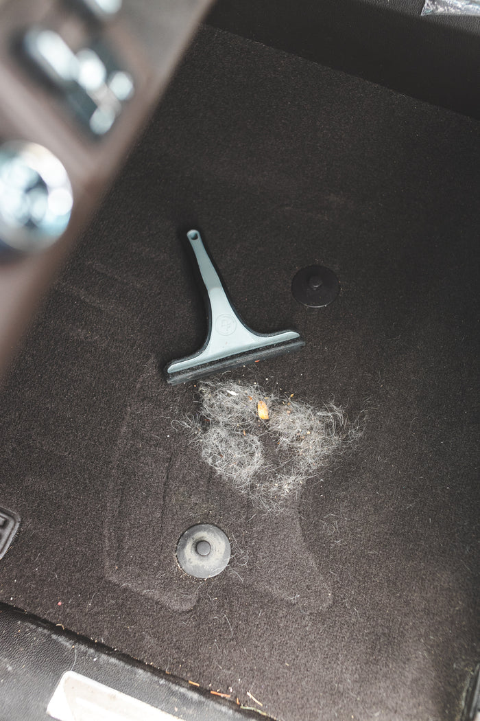 Detail Factory Pet Hair Rake used on the carpeted ground of a vehicle.