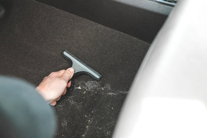 Detail Factory Pet Hair Rake used on the carpeted ground of a vehicle.