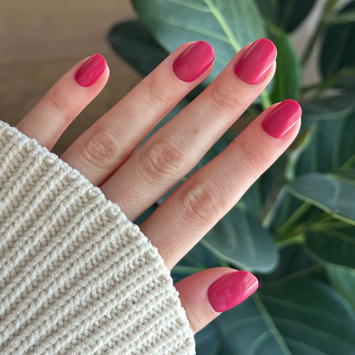 Roar - Tab Press-On | Extra Short | Round in vibrant pinky red press-on nails shown on hand with cozy sweater cuff