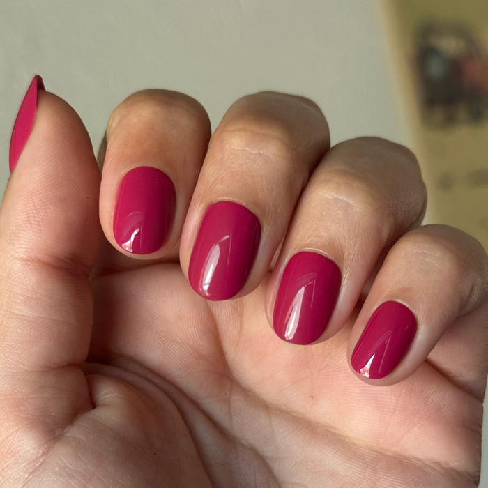 Roar - Tab Press-On | Extra Short | Round in bold pinky red on natural hand showing glossy finish press-on manicure