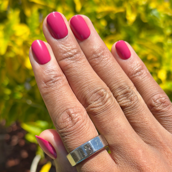 Roar - Tab Press-On | Extra Short | Round in bold pinky red press-on nails on natural hand outdoors with silver ring
