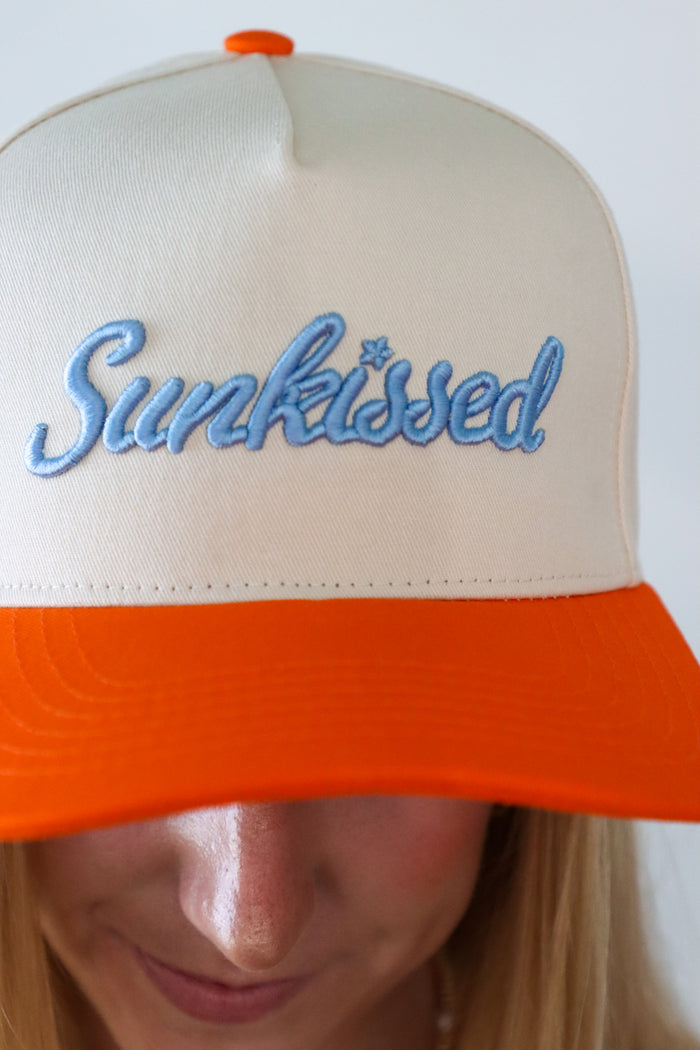 Beige and orange cap with 'Sunkissed' text on a plain background