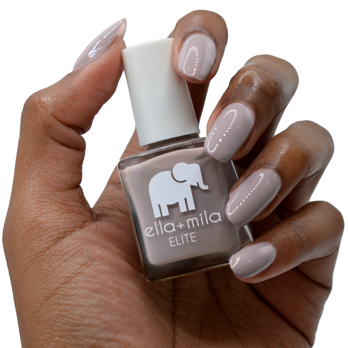 Traveler taupe purple nail polish on a deep skin tone, hand holding the bottle