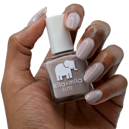 Traveler taupe purple nail polish on a deep skin tone, hand holding the bottle