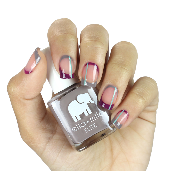 Traveler taupe nail polish with pink and purple abstract accent nail art, holding the bottle