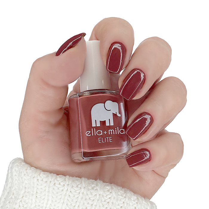 Wanderer muted brick red nail polish manicure on a light skin tone with the bottle