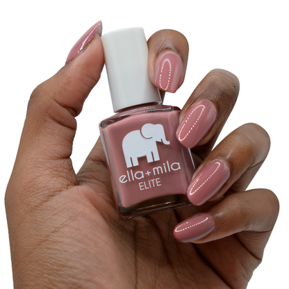 Wanderer brown brick red nail polish on a deep skin tone, hand holding the bottle