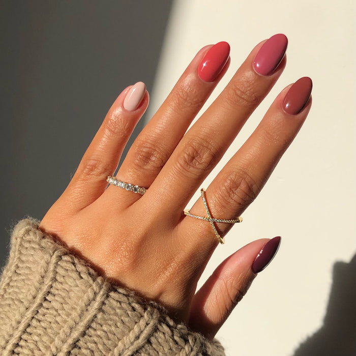 Wanderer brick red and nude mix-and-match manicure with rings in sunlight
