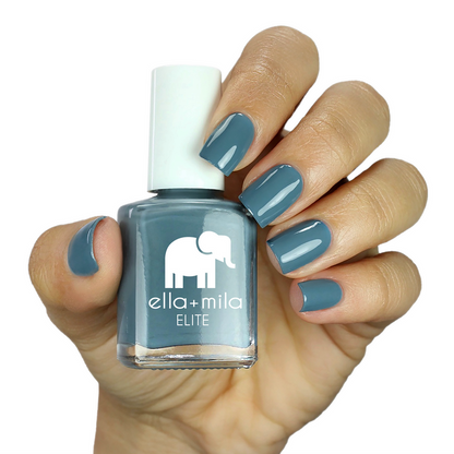 Window Seat grey blue nail polish on a medium skin tone, hand holding the bottle