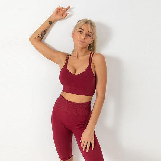 A woman wearing a red yoga set which includes a crop top and leggings.