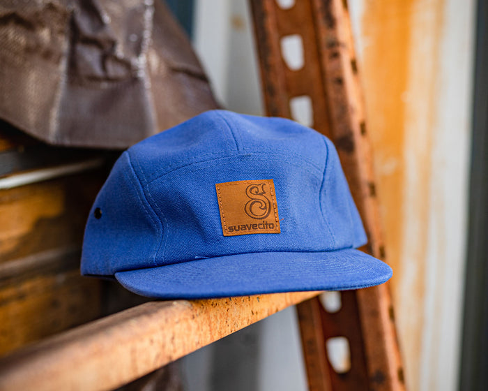 blue suavecito hat with black text and brown background "S suavecito"